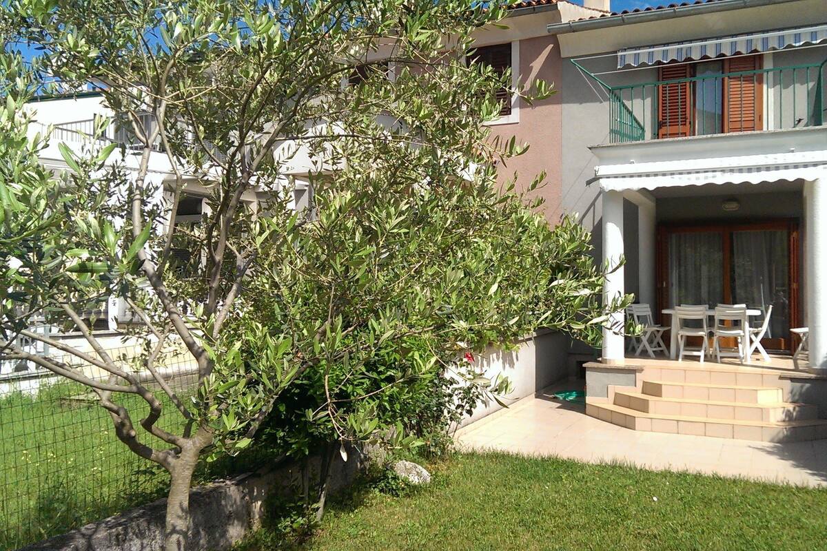 A two-story building with a balcony and a small garden area.