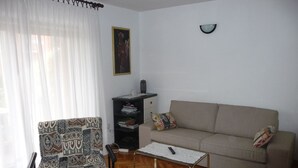 A living room with a patterned armchair, a sofa, a coffee table, and a bookshelf. - Apartment Anto (Umag)