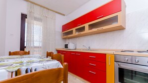 A kitchen with red cabinets, a microwave, and an oven. - Apartments Kursan (Okrug Gornji)