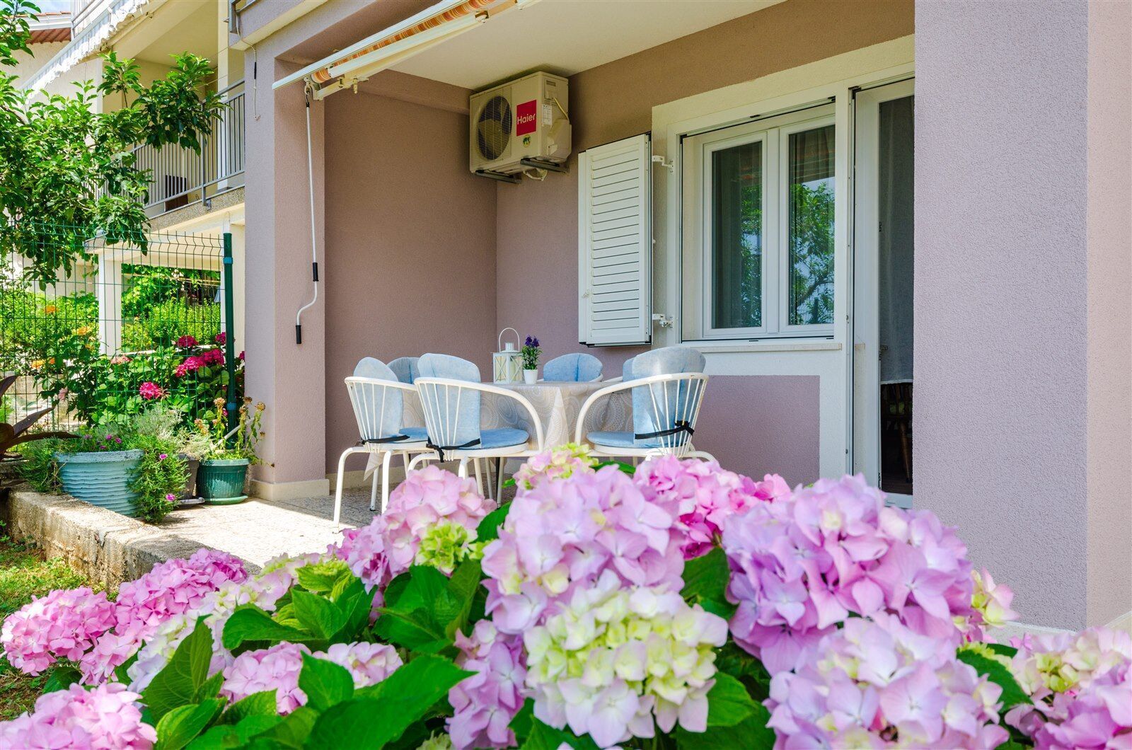 A balcony with white chairs, a table, and a potted plant.