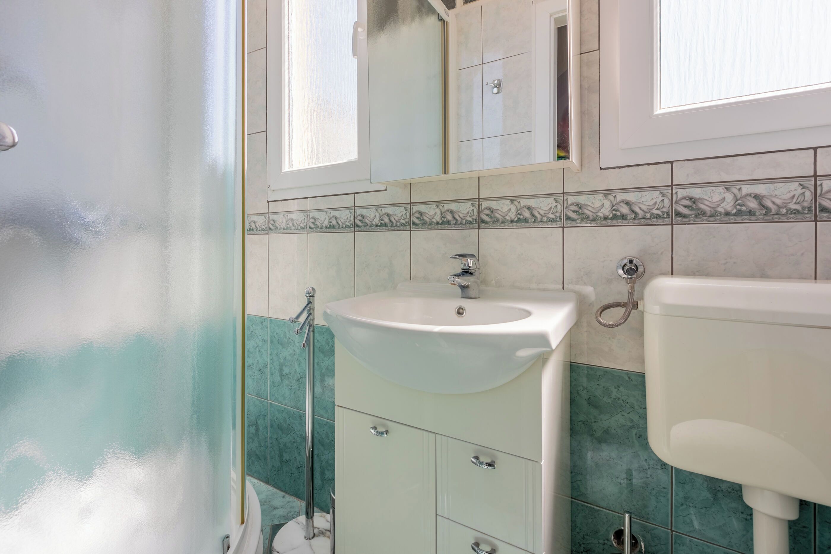 A bathroom with a white sink, a mirror, and a toilet.