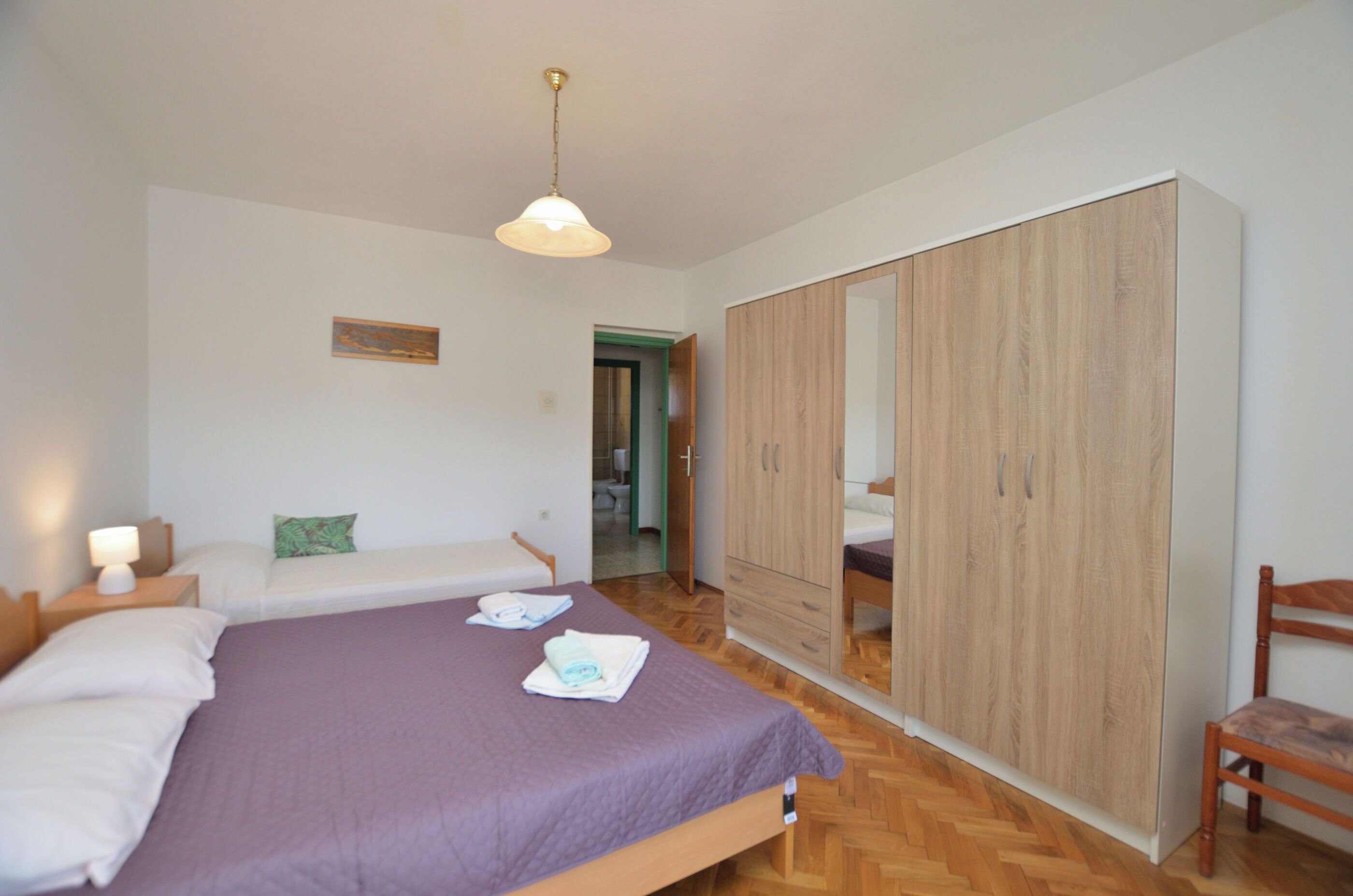 Una camera da letto con un letto, un armadio, una sedia e un comodino.