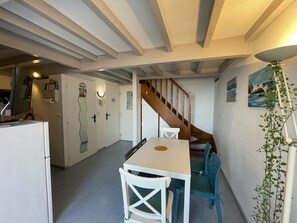 A compact kitchen with a dining area, a staircase, and a wall-mounted plant.