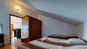 A bedroom with a large bed, wooden wardrobe, and a small bedside table. - Villa Pave (Jadranovo)