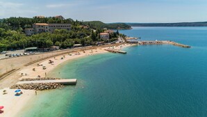 A coastal town with a sandy beach, a pier, and buildings on a hillside. - Villa Pave (Jadranovo)