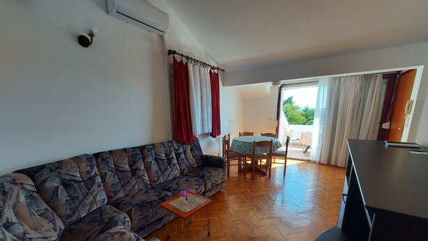 A living room with a patterned sofa, a small table, a dining area with chairs, and a TV. - Villa Pave (Jadranovo)
