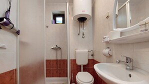 Un baño con ducha, inodoro, lavamanos y espejo.