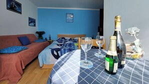 Un dormitorio con cama, una mesa con copas y botellas de vino, un sofá y una pared con cuadros.
