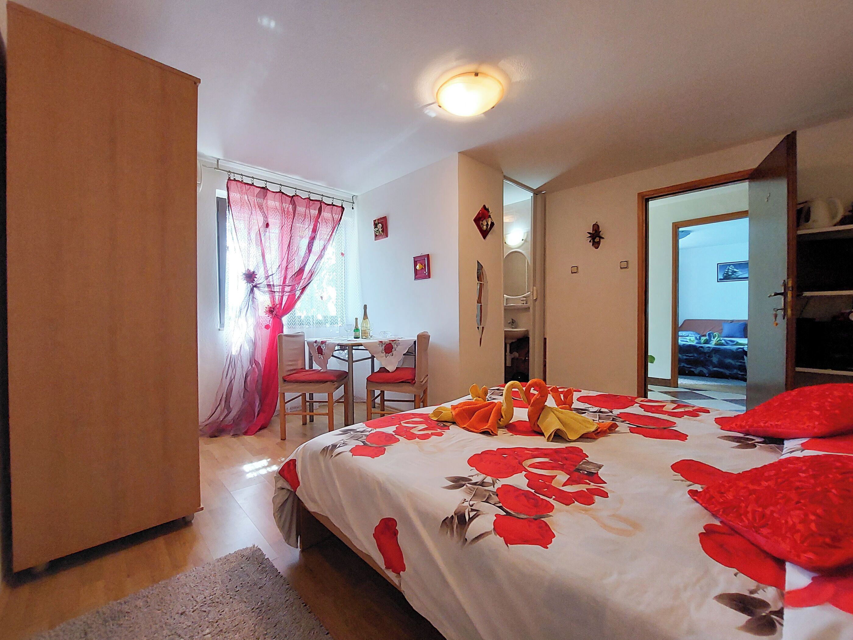 A bedroom with a bed, a desk, and a chair. There is a door leading to another room.