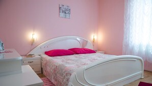 A bedroom with a white bed, pink walls, and two bedside lamps. - House Denis (Crikvenica)