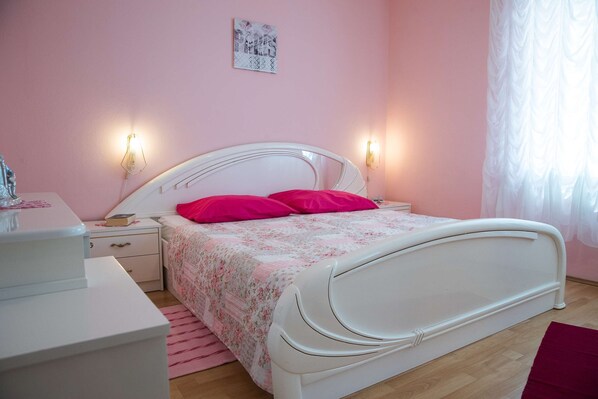 A bedroom with a white bed, pink walls, and two bedside lamps.