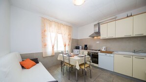 A compact kitchen with a dining table, chairs, a microwave, a coffee maker, and a dishwasher. - House Denis (Crikvenica)