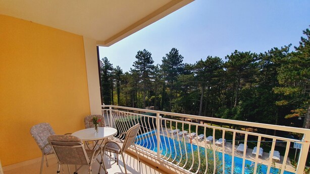Un balcone con piscina, sedie in vimini e un tavolo.