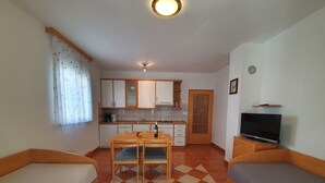 Una stanza compatta con angolo cottura, zona pranzo e due letti singoli.
