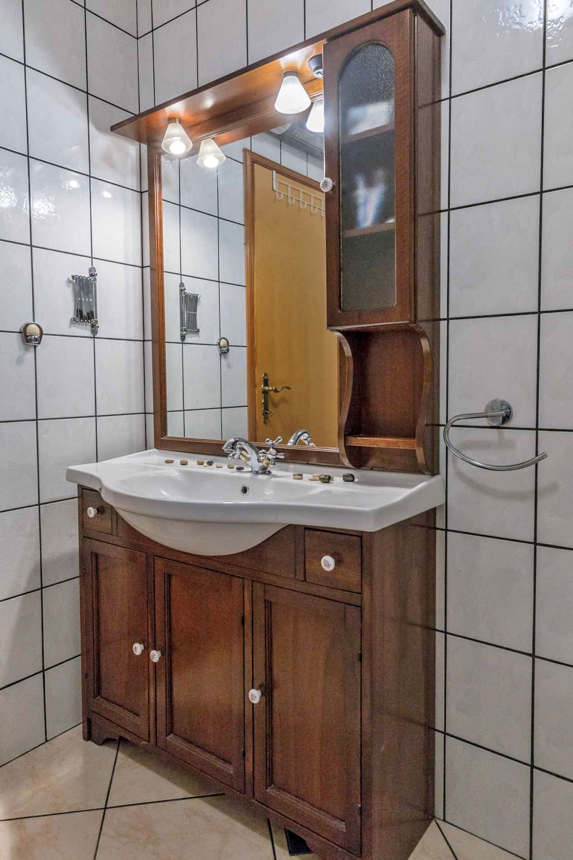Un baño con tocador de madera, un lavabo blanco y un espejo con iluminación.