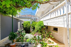 A courtyard with potted plants, a staircase, and a building with a balcony. - Apartment Miro and Marino (Trogir)