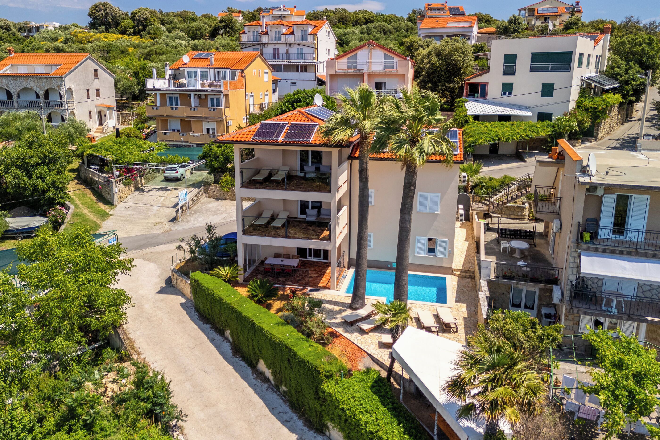 A residential building with a swimming pool, multiple balconies, and solar panels.