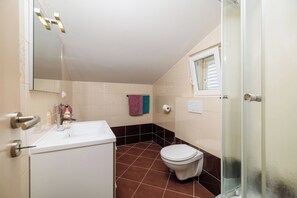 A bathroom with a white sink, a toilet, a glass shower enclosure, and a mirror. - House Davorka (Supetarska Draga)