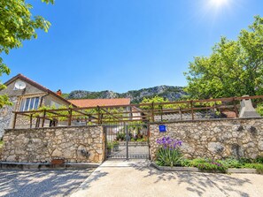 A stone-walled building with a tiled roof, a gated entrance, and a clear view of the surrounding landscape.