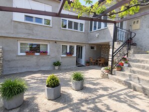 A courtyard with a pergola, potted plants, a staircase, and a dining area.