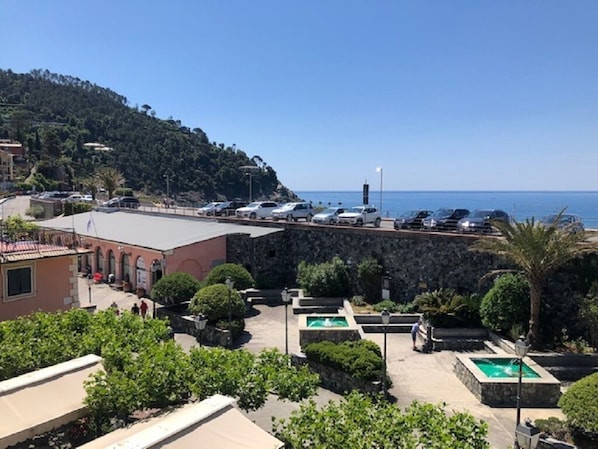 A coastal hotel with a pool, a parking area, and a view of the sea.