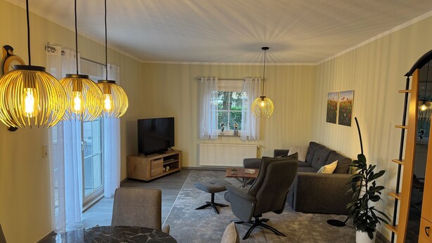 Ein modernes Wohnzimmer mit Fernseher, Sofa und Essbereich.