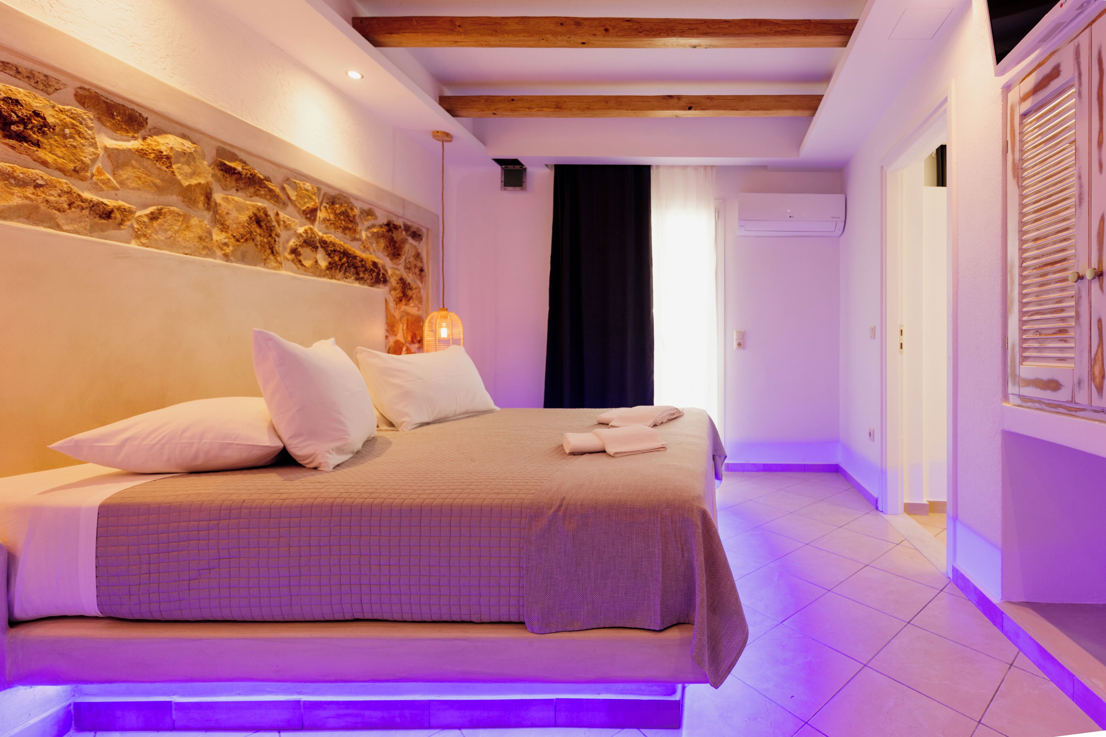 Un dormitorio con cama, almohadas, una lámpara de pared y una pared decorativa de piedra.