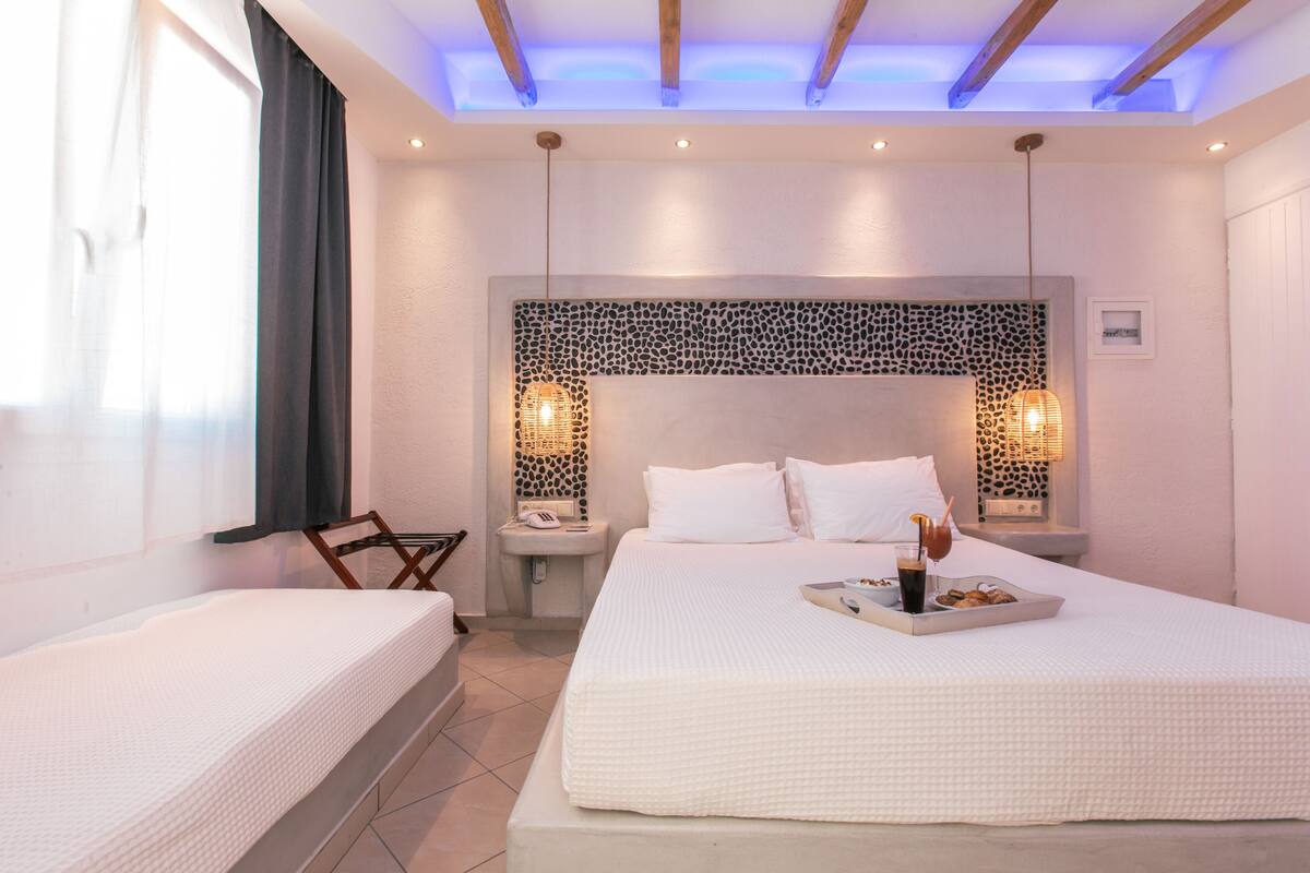 Une chambre d’hôtel avec un grand lit, des tables de chevet, une chaise et un panneau décoratif au mur.