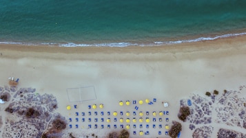 En la playa, arena blanca, sillas reclinables de playa, sombrillas