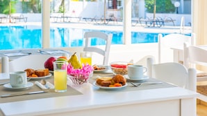 A breakfast table with plates of food, a glass of juice, and a fruit bowl. - Mikri Vigla Hotel Beach Resort (Naxos)