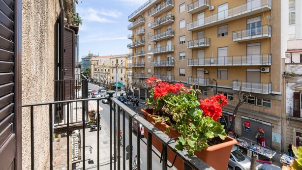 Un edificio de varios pisos con balcones, vista a la calle y cielo despejado.