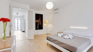 Un dormitorio moderno con cama, mesita de noche, lámpara y vista al pasillo.