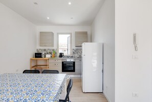 A compact kitchen with a microwave, stove, oven, and refrigerator. There is a dining area with a table and chairs.