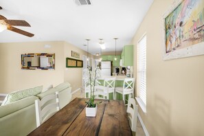 A dining area with a wooden table, white chairs, and a potted plant. - 🐟Walk to Beach~Pool + Corner Balcony~PRIME Location~Rollin Tide B9 (Santa Rosa Beach)