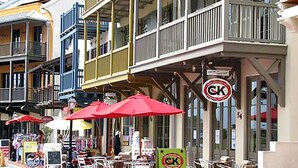 A street with outdoor seating, red umbrellas, and a signboard with 'CK' logo. - 🐟Walk to Beach~Pool + Corner Balcony~PRIME Location~Rollin Tide B9 (Santa Rosa Beach)