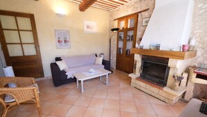 Una sala de estar acogedora con chimenea, un sofá, una mesita de centro y un sillón de mimbre.