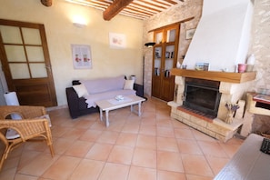 Una sala de estar acogedora con chimenea, un sofá, una mesita de centro y un sillón de mimbre.