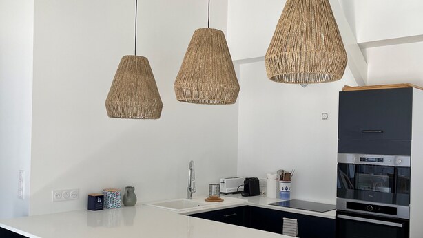 A modern kitchen with a central island, bar stools, and pendant lighting. - Charming villa in Cap-Ferret (Lège-Cap-Ferret)