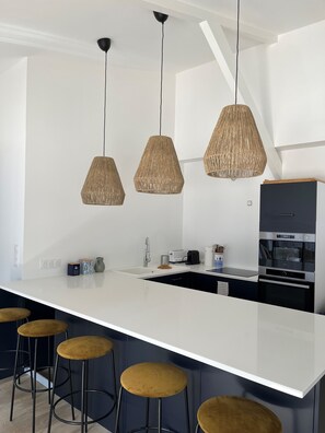 A modern kitchen with a central island, bar stools, and pendant lighting.