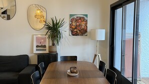 A modern dining area with a wooden table, black chairs, a potted plant, and artwork on the walls. - Charming villa in Cap-Ferret (Lège-Cap-Ferret)