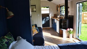 Et hyggeligt værelse med seng, sofa, spiseplads med bord og stole samt et køkken med komfur.