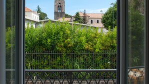 A balcony with a hot tub and a view of a church tower.