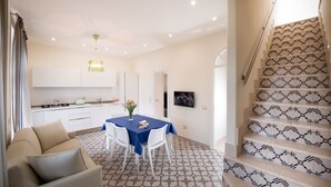 A modern kitchen with white cabinets, a dining table with chairs, and a staircase with patterned railings.