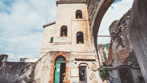 A historic building with a central tower, arched windows, and a green door.