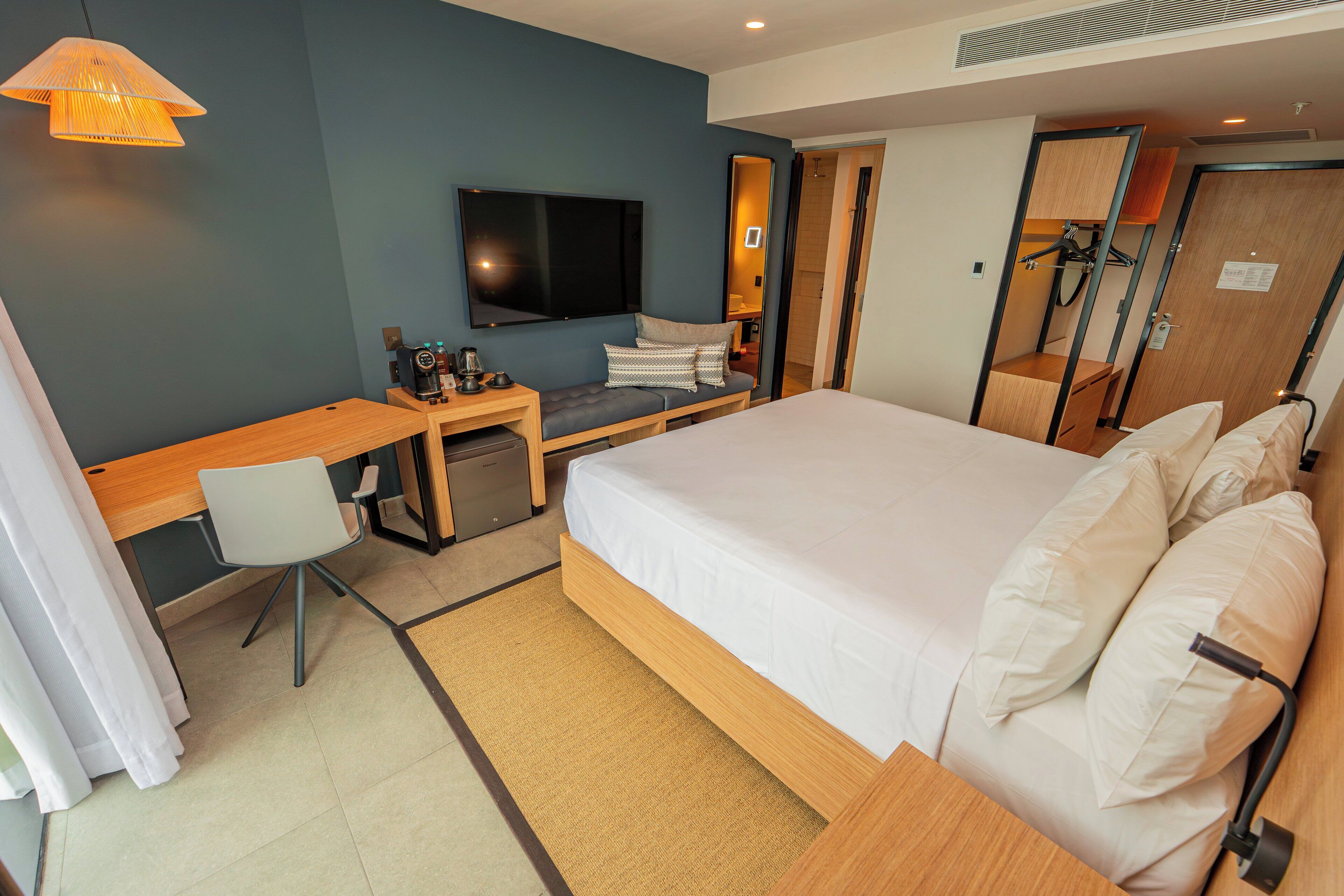 A hotel room with a bed, a desk, a chair, a television, and a wardrobe.