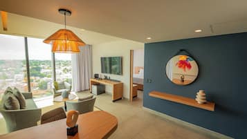 A modern hotel room with a large window, a dining area, a bed, a desk, and a TV.