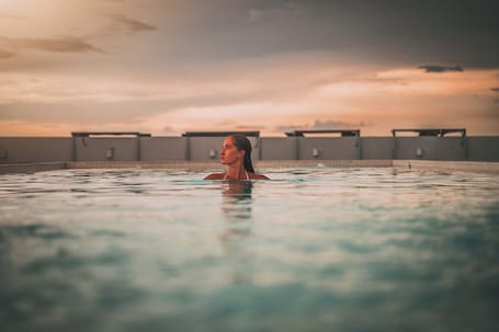 Una piscina al aire libre, sombrillas, sillones reclinables de piscina. Crowne Plaza Merida by IHG