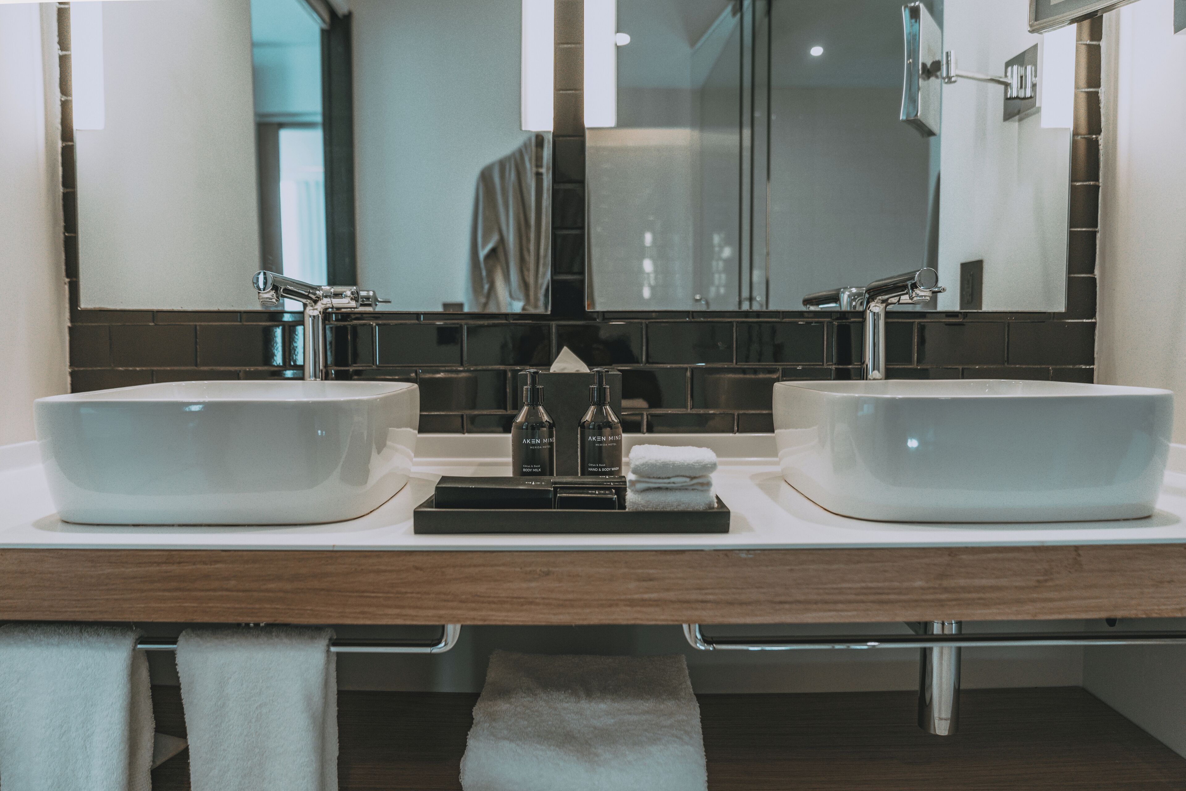 A bathroom with two sinks, a mirror, and a tray with toiletries.