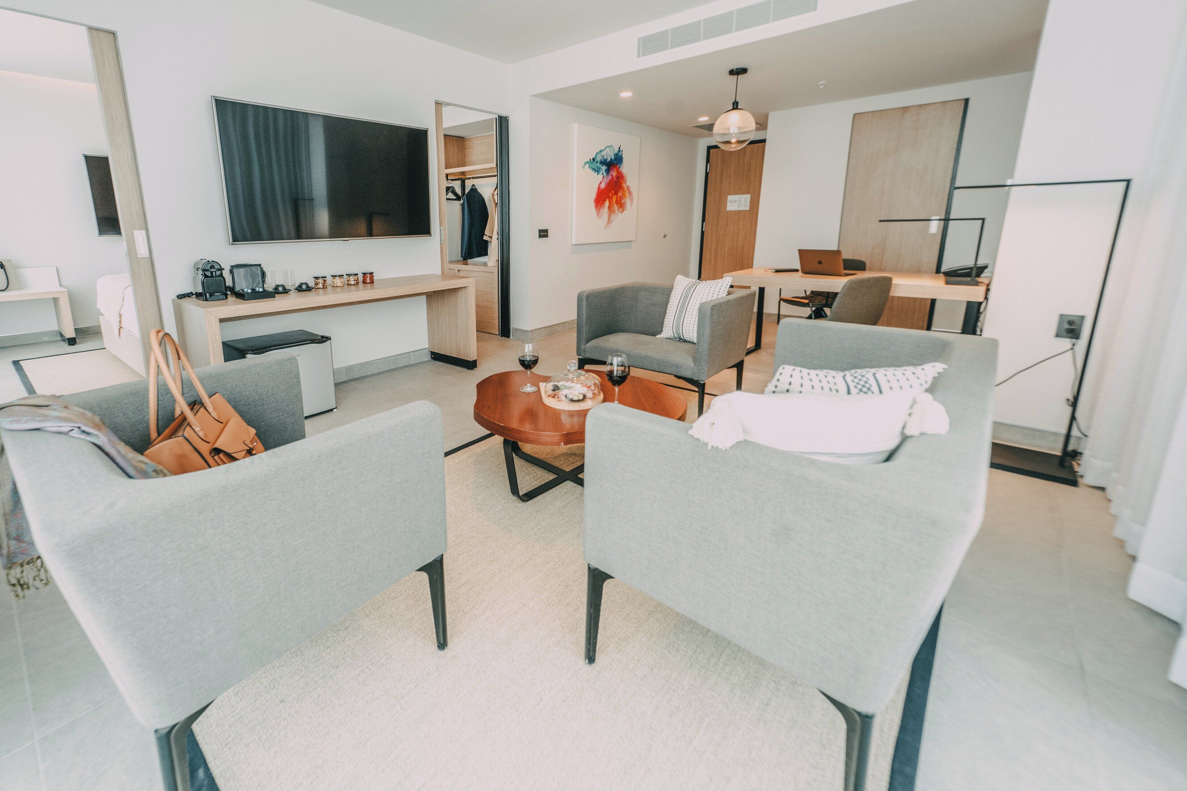 Uma sala de estar moderna com sofás cinzas, uma mesa de centro e uma TV fixada na parede.