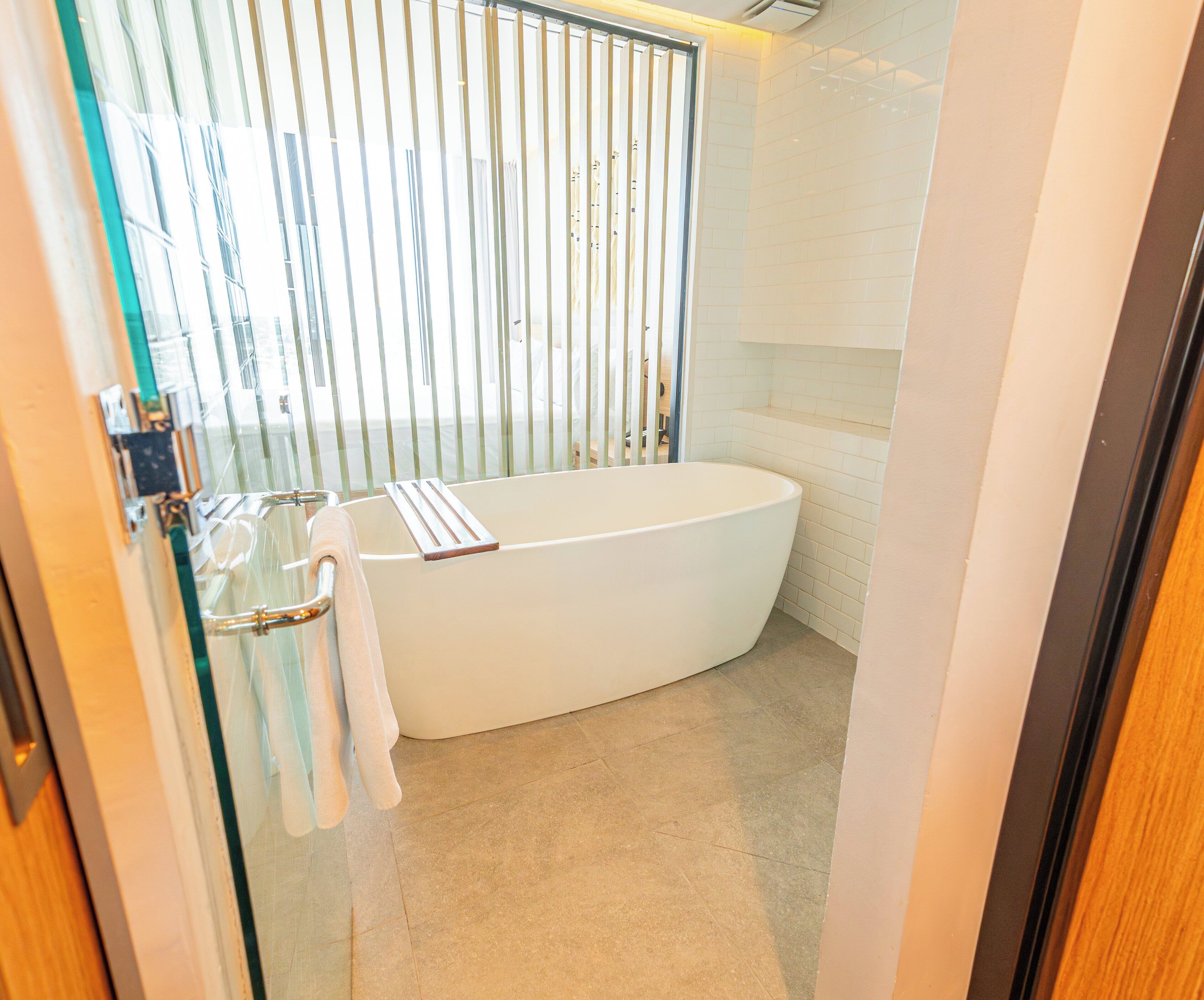 A modern bathroom with a freestanding bathtub, a glass shower enclosure, and a tiled floor.